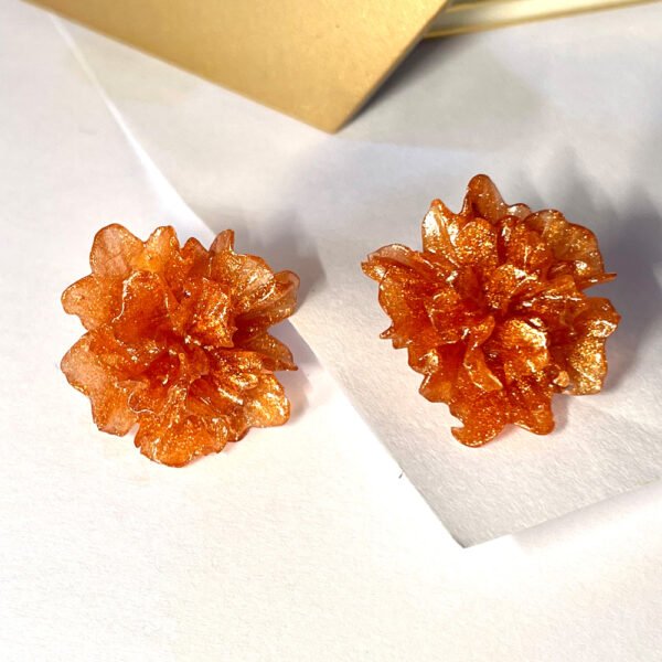 Handmade orange resin flower stud earrings with glitter, displayed on a white background.